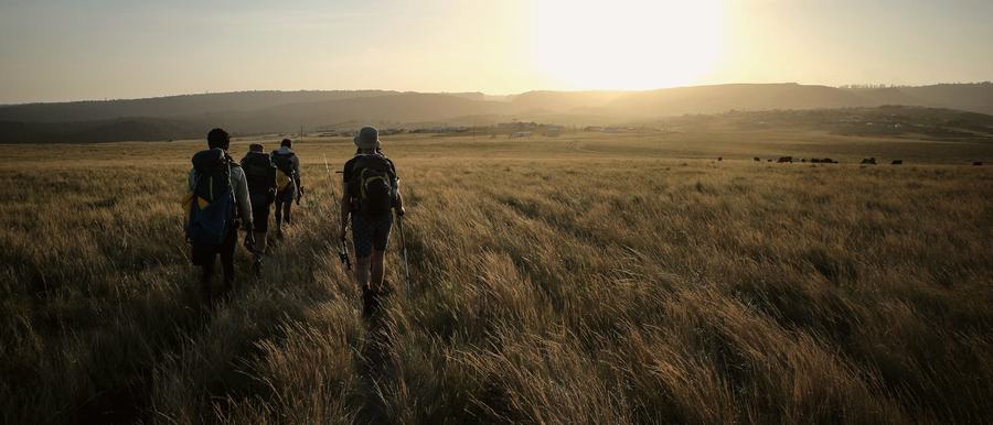Grupo de pessoas caminhando junto por um campo aberto ao entardecer